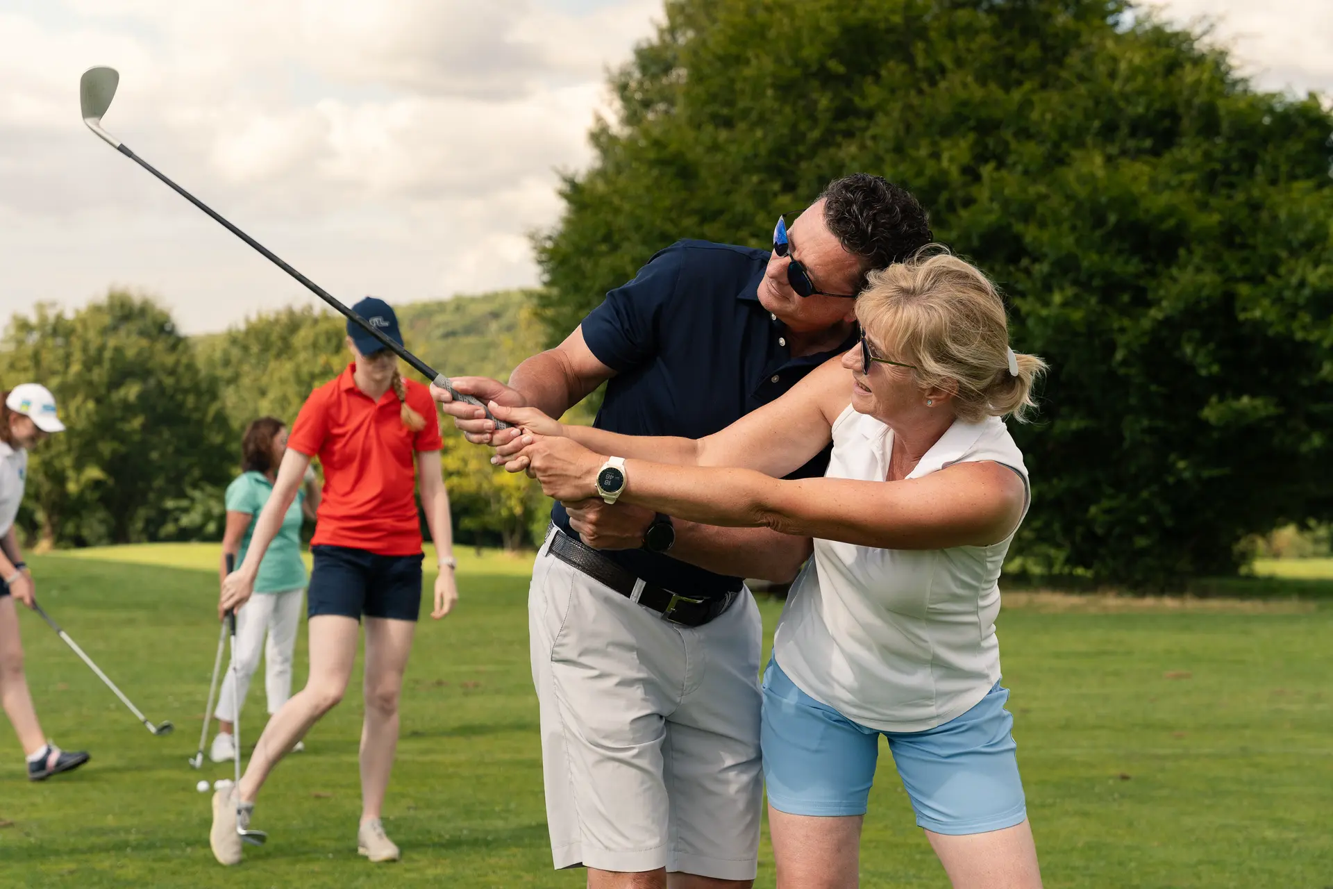 Golflehrer zeigt einer Frau die richtige Haltung des Schlägers